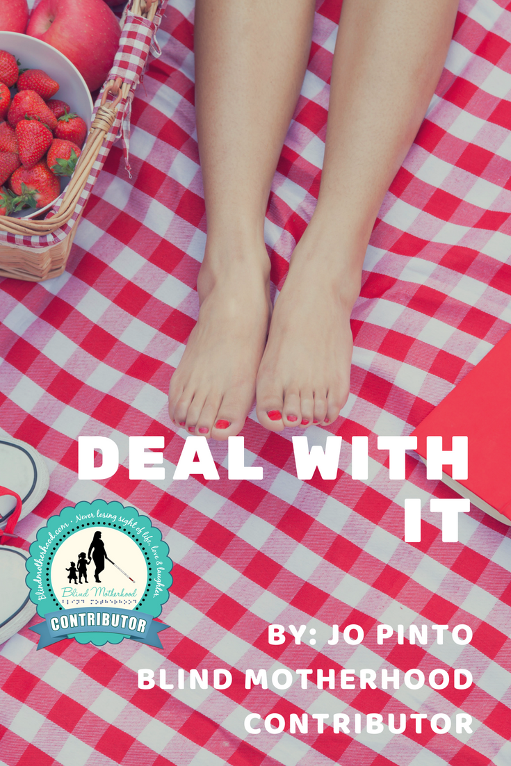 ID: ID: Bare feet with red painted toe nails sitting on a red checkered picnic tablecloth.