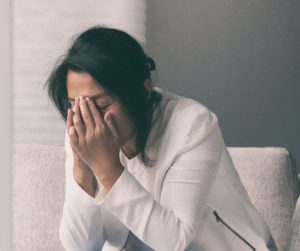 Woman sobbing with her heard buried in her hands.