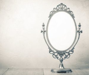 Table top silver mirror on gray background.