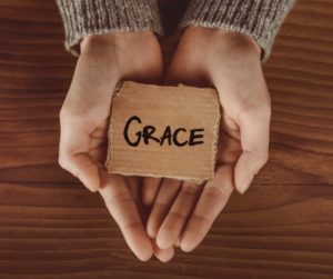 Hands opened with a piece of cardboardthat reads "grace."